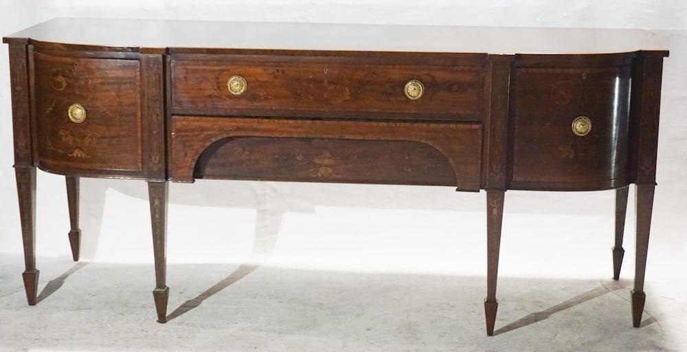 English George III Style Inlaid Mahogany Sideboard: Circa 1850. Having a shaped top with satinwood banded above lower case housing two long drawers at center flanked by a handsome bottle drawer at right complete with dividers and a single hinged door a