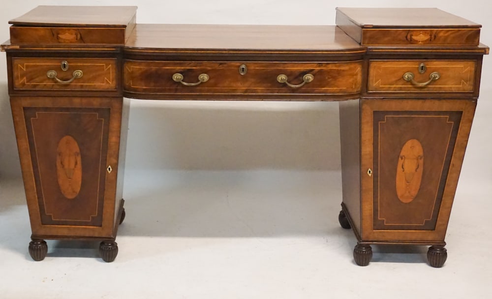 Fine English Regency Inlaid Mahogany Sideboard: Circa 1830. Having a brilliantly inlaid case with double pedestal configuration. The piece having three drawers over two hinged doors the right of which houses a brilliant lead lined wine bottle drawe