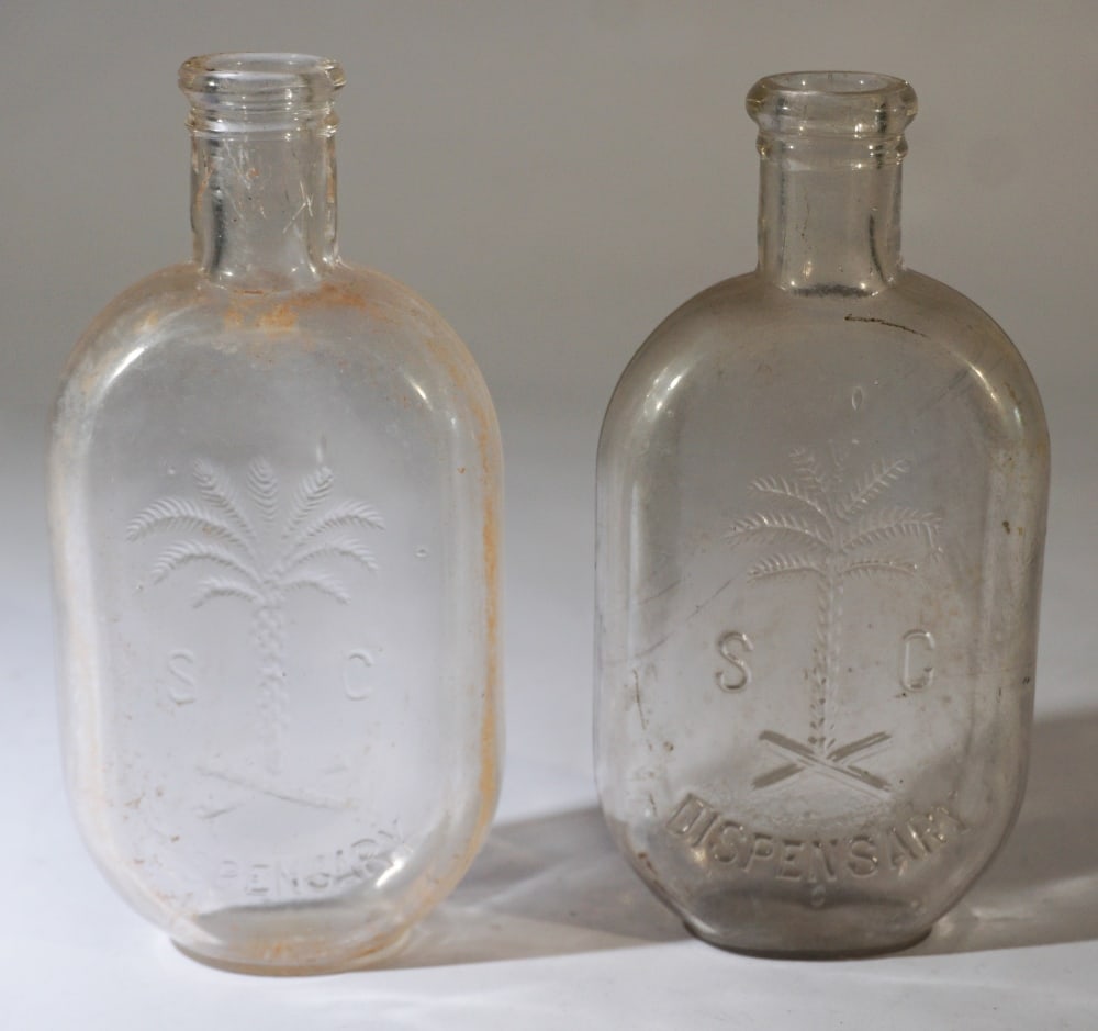 Two Antique South Carolina Dispensary Bottles: Smaller size JoJo flasks each with a handsome palmetto seal. Very good condition. One having ribs at the interior of the spout as made. One is marked E.P. Jr. and Co. H6 3/4" H6 7/8" Sold from the col