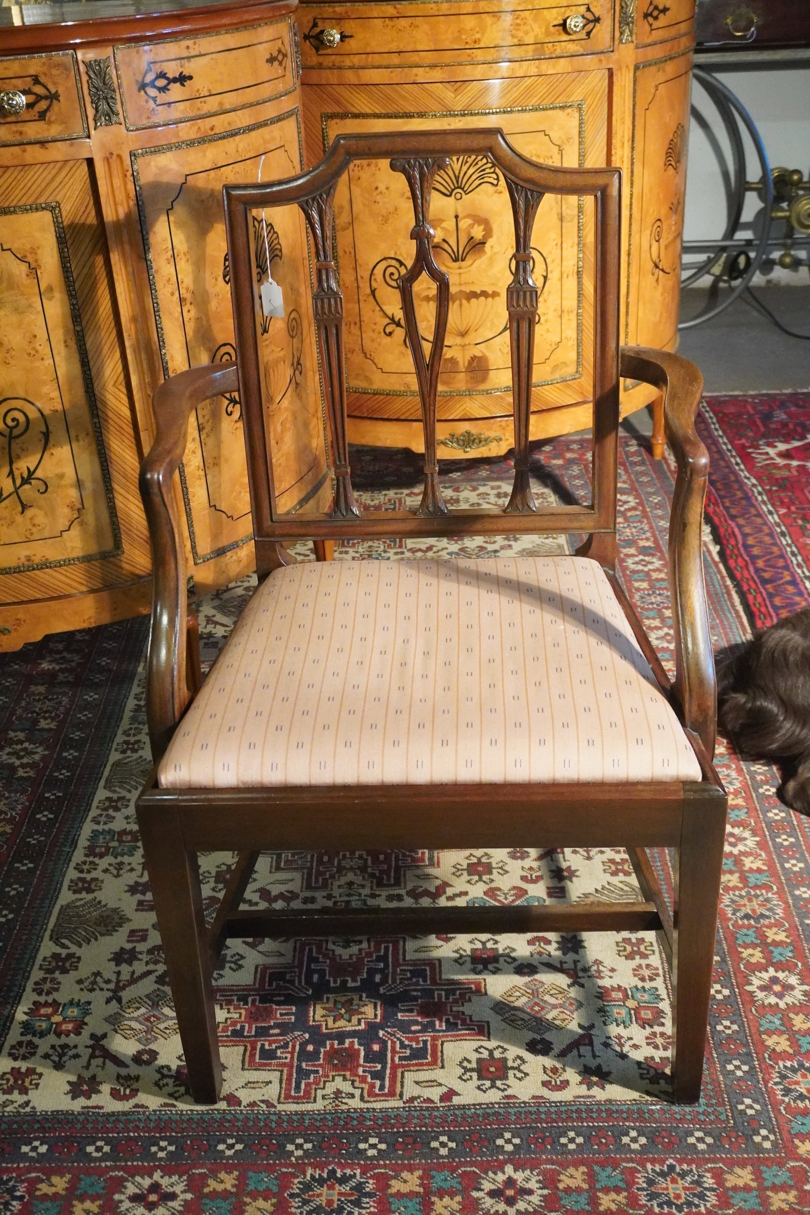 Handsome Federal Carved Mahogany Armchair: Circa 1810. Having a brilliantly carved back with nice feathering over the arms and upholstered seat atop nicely tapered legs. The back legs have been professionally restored. H36 1/4" W23" D20" Sold 