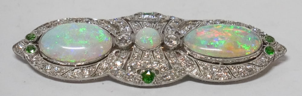 Exceptional Frank Walter Lawrence Platinum Diamond Opal & Emerald Brooch: Art Nouveau piece having been meticulously crafted housing two excellent cabacho opals with excellent color and fire the broach housing two ctw of round cut diamond and 3/4 ctw of round cut emeralds.