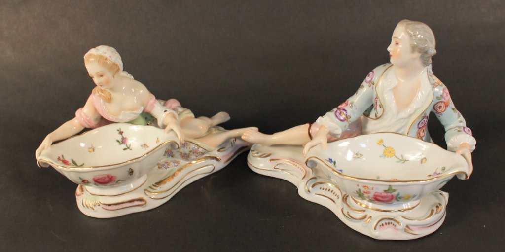 Pair Porcelain Figural Master Salt Cellars: in the Meissen style. bearing mark on base. a gentleman and a lady reclining next to floral-decorated bowls. H5” W7”