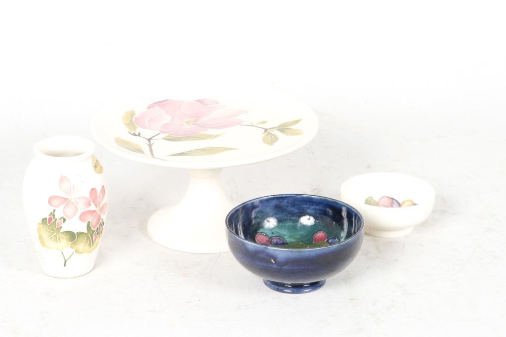 Four Moorcroft Pottery Items: includes: small cake stand, small vase in hepatica pattern, small bowl in grape pattern, and small bowl in anemone pattern. H to 4" (cakestand) From the Estate of Anita Hill, Jupiter, Florida.