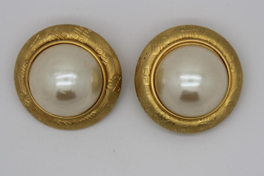 Vintage Gold Givenchy Faux Pearl Logo Clip Earrings: Vintage Givenchy large clip earrings Continuous Givenchy logo pattern 1/4" around the edge with a large faux pearl in the center Measures 2" in diameter Stamped Givenchy on back