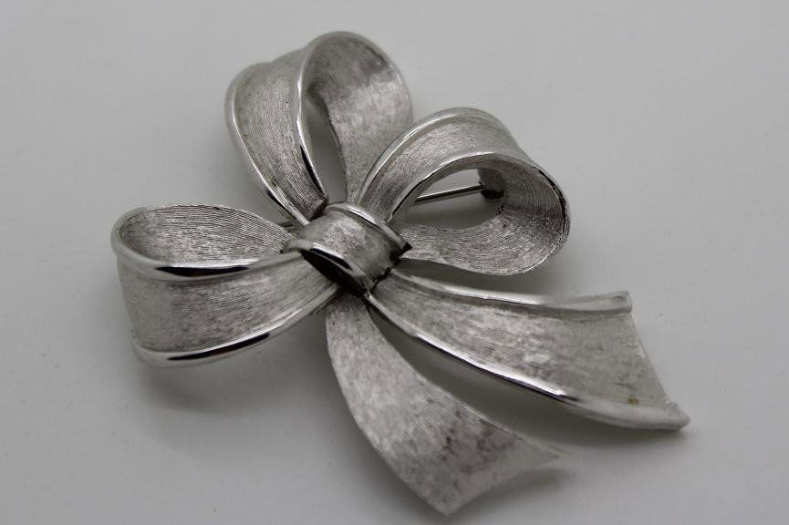99: Vintage Silver ToneTrifari Bow Brooch: Trifari silver-tone Bow brooch. Measures 2 ½” long and 1 ¾’ wide.