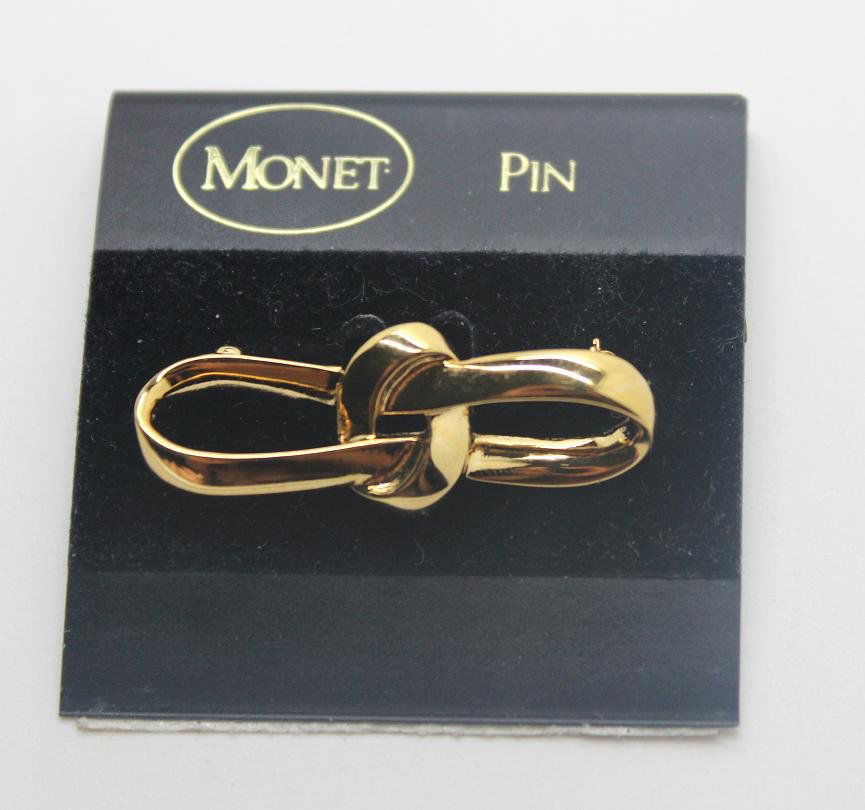 264: Vintage Monet Gold Tone Bow Pin Brooch: Signed Monet. Unworn gold tone bow pin brooch. 1 1/2" wide, 1/2" in length.