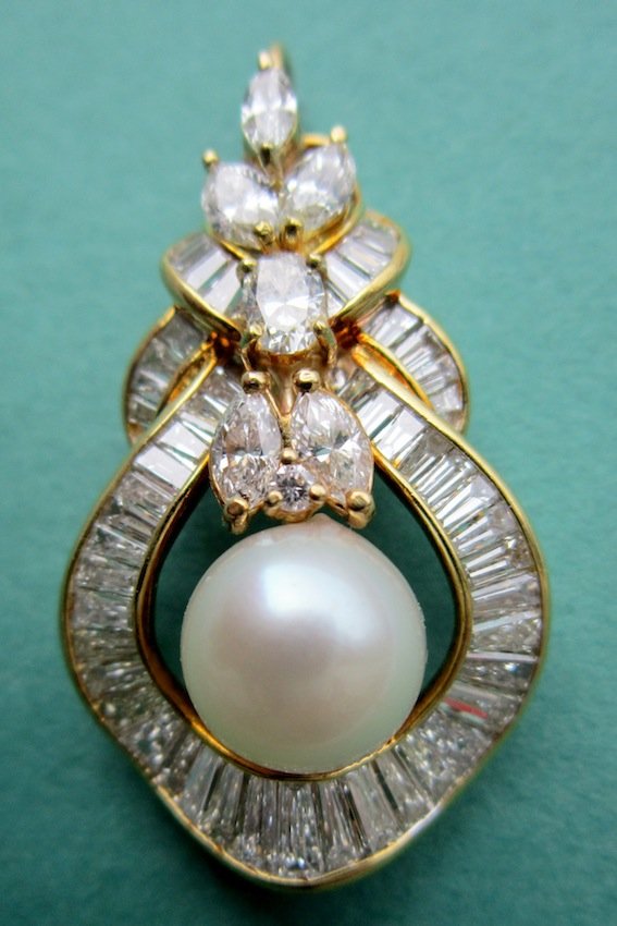 18K Yellow Gold Pearl and Diamond Pendant: With 10mm Akoya cultured pearl and 1 round diamond, 1 oval diamond, 3 marquis diamonds, and 51 baguette-shaped diamonds. 5.15 CTW, VSI-SIZ, H-J, 5.7 DWT. Dimensions: 1 1/2" x 3/4" (item matches lot #1