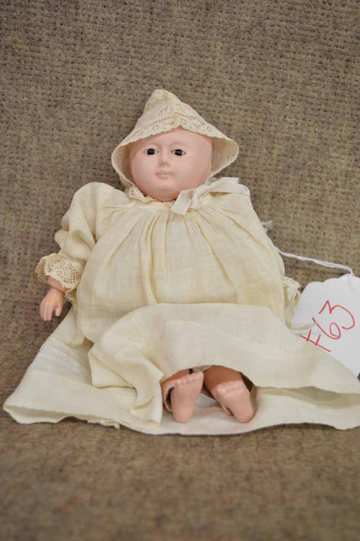 MOTCHMANN BABY: 8 1/4" MOTCHMANN BABY ON PAPIER MACHE & WOOD BODY W/ FLOATING HIPS - FLOATING HIPS, PUPILLESS BLACK GLASS EYES, C/M, JNTD AT WRISTS & ANKLES, LOOKING BALD, WEARING OFF-WHITE COTTON DRESS W/ LACE ACCEN