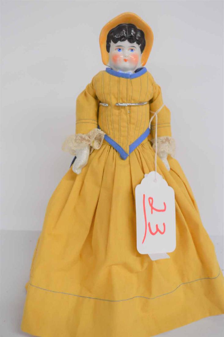 BLACK HAIRED BONNET HEAD: 12 3/4" BLACK HAIRED BLUE EYED BONNET HEAD ON CLOTH BODY W/SEWN ON OIL CLOTH "SHOES" THAT SHOW STITCHING REPAIR,MOLDED BONNET IS WHITE W/ORANGE RIM, PINK BOW ON TOP, BLUE BOW AT NECK, CHINA ARMS ENDIN