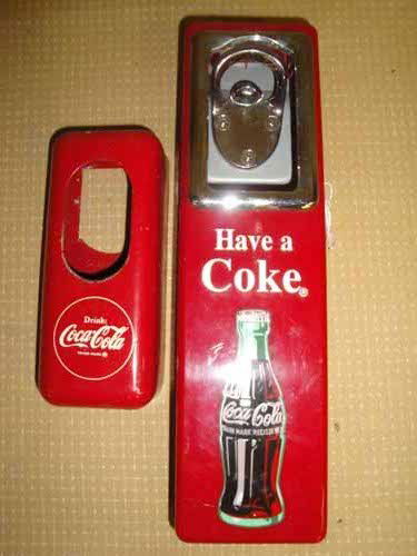(2) Coca Cola Bottle Cap Openers: (2) Coca Cola Bottle Cap Openers with Holders - (1) Metal 6"H x 2 1/2"W/(1) Plastic 10 1/2"H x 3" W