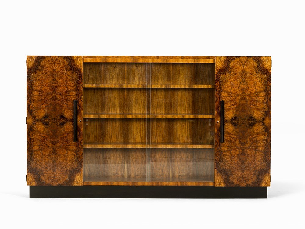 Art Déco Bookcase with Nutwood Veneers, Germany, c.: Nutwood, root wood and cherry veneers, glass, lacquer Germany, around 1930 Metal plate inside the right front door, inscribed ‘Münch MM Möbel’ Art Déco bookcase with three part corpus Two keys 