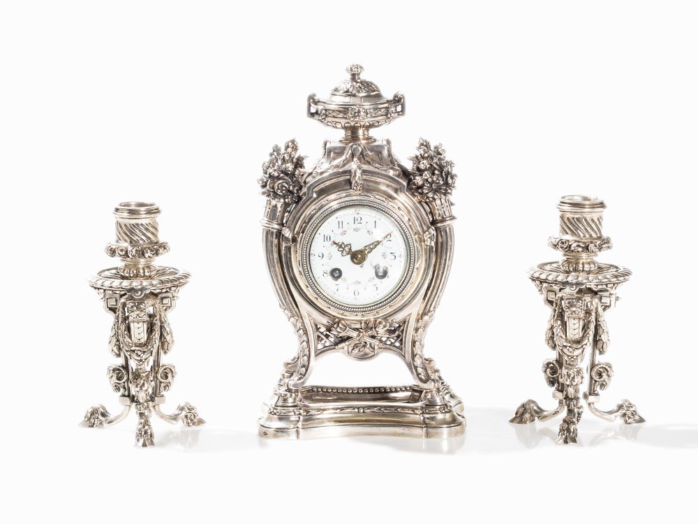 A Louis XVI-Style Table Clock with Canbelabras, France,: Silver, cast, enamel, brass, glass, cut France, late 19th century Alphonse Debain – Silversmith, active from 1883 until 1911 Hallmarked with maker’s mark, presumably standard (illegible) and furth
