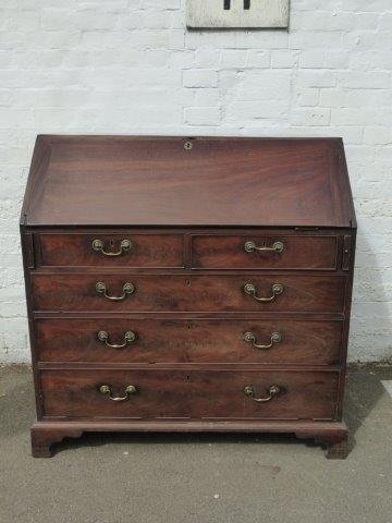A Georgian mahogany bureau with fitted interior, the: A Georgian mahogany bureau with fitted interior, the fall above two short and three long drawers raised upon bracket feet.