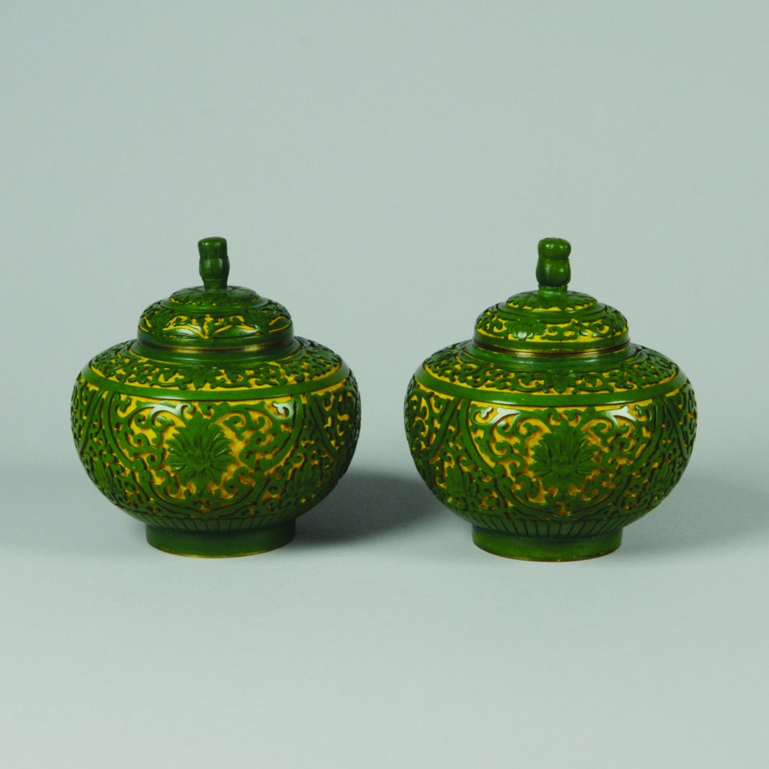 PAIR OF CARVED GREEN CINNABAR LACQUER JARS: Very rare green cinnabar lacquer with yellow ground. Brass bodied. Blue glazed base and interior. H: 5 ½" D: 5"