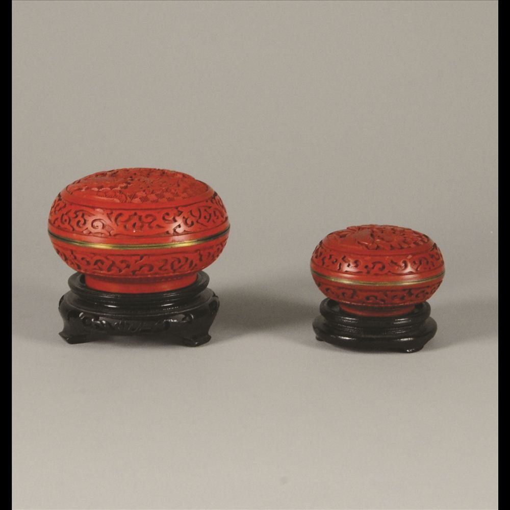 PAIR OF CARVED CINNABAR INKPAD ROUND BOXES: One small, one large. Bronze based with all over floral designs and cloisonné enamel inner lining D: 4” (large) D: 3” (small)