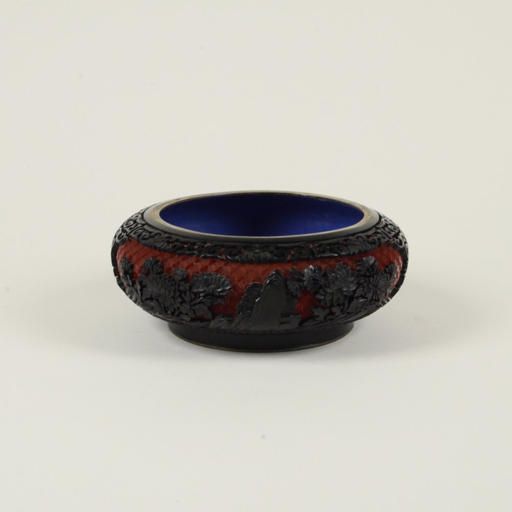 CARVED CINNABAR LACQUER WATER POT: Brass bodied. Black lacquer with red ground. Floral designs with double-sided panels. Glazed bottom and interior. D: 8"