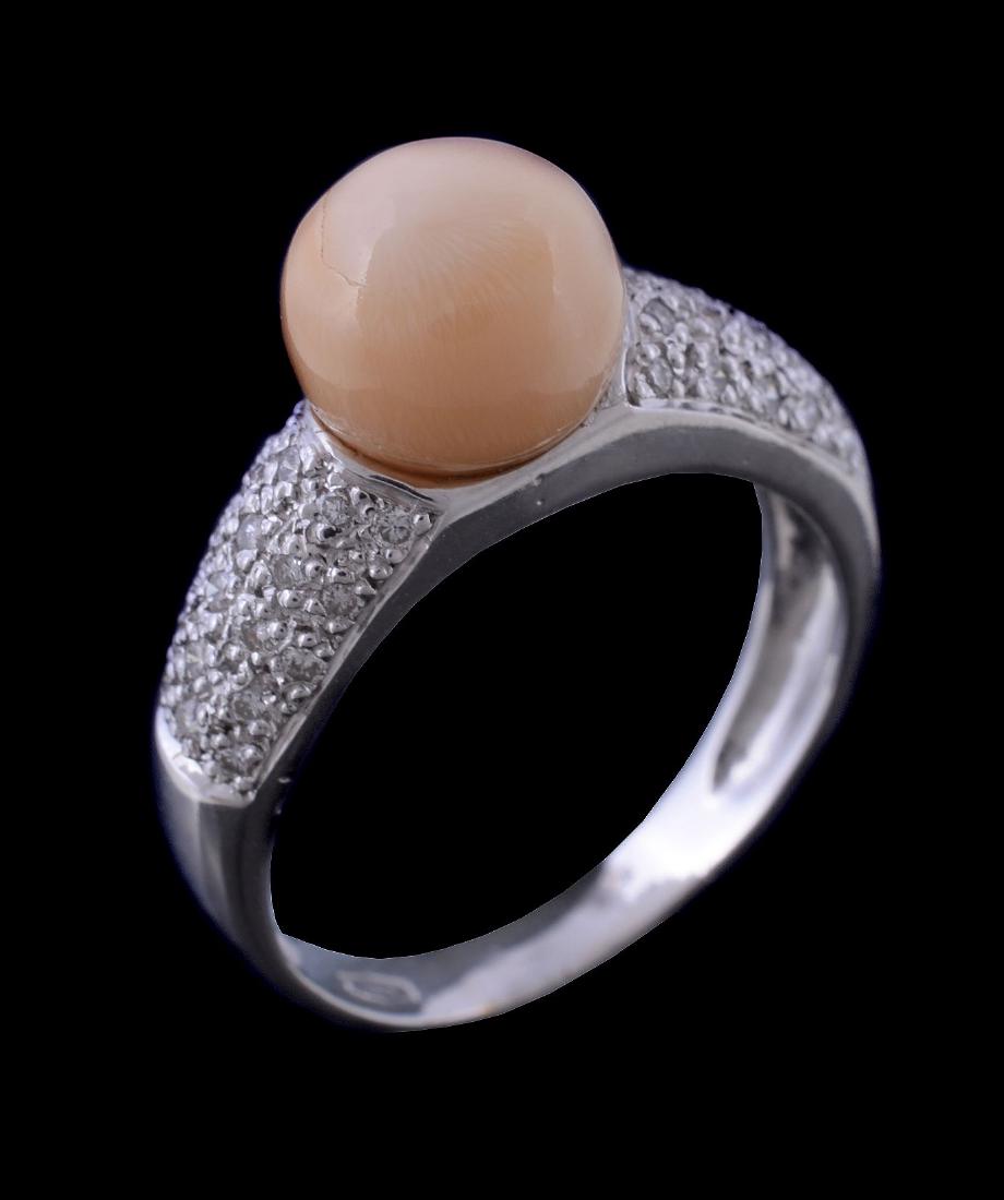 A natural saltwater non-nacreous pearl and diamond ring: A natural saltwater non-nacreous pearl and diamond ring, the light orange pearl measuring 8.2-8.3 x 7.4mm, between brilliant cut diamond set shoulders, stamped 750, finger size M 1/2 Offered for sale 