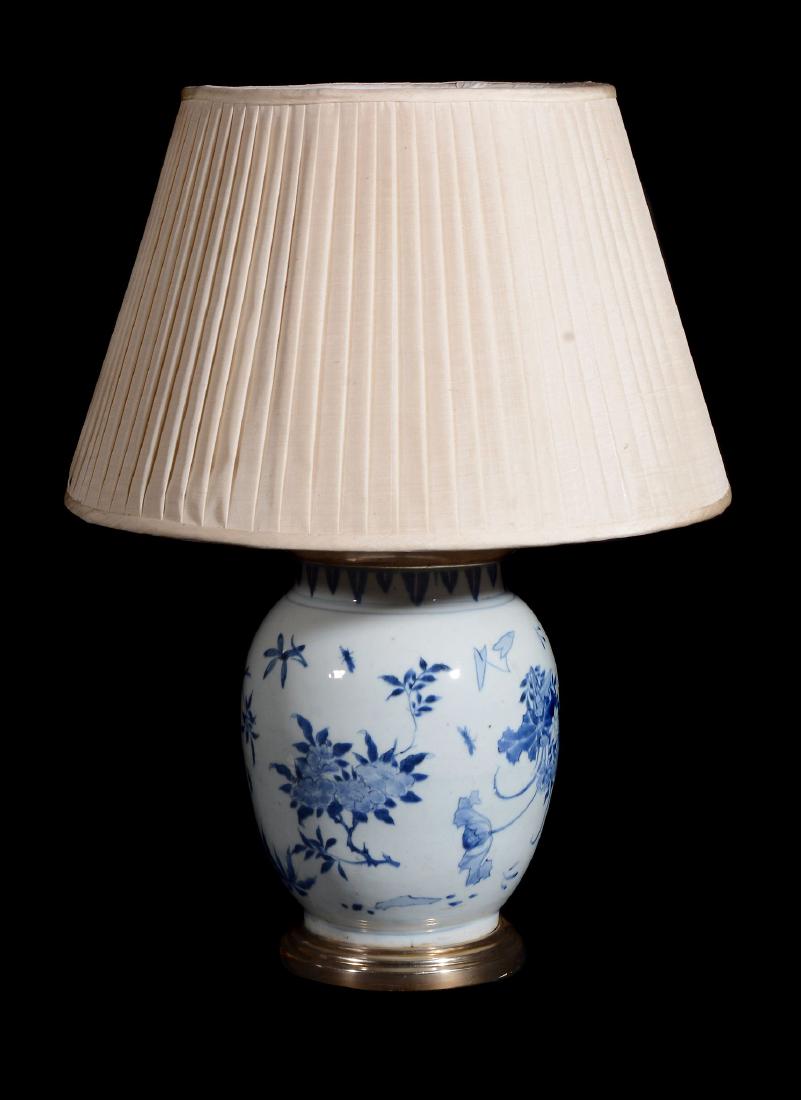 A Chinese blue and white ovoid jar , 17th century: A Chinese blue and white ovoid jar , 17th century, painted with scattered floral sprays beneath a lappet border at the rim, drilled and mounted as a lamp, 29cm high
