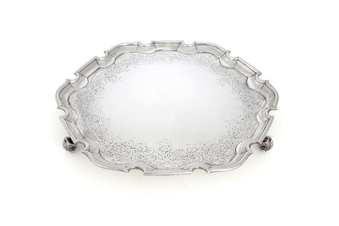 A late George II silver shaped circular salver by John: A late George II silver shaped circular salver by John Jacob, London 1753, with a raised moulded rim, a plain incurve, engraved with a band of flowering scroll foliage, on four scroll and leaf feet, s