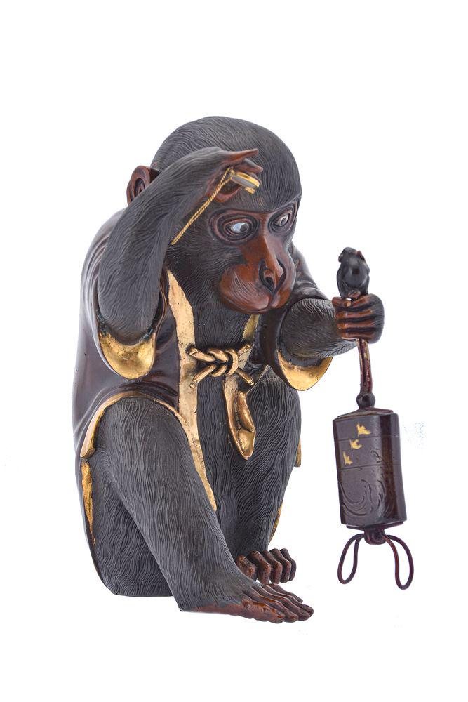 A Japanese Bronze Model of a Macaque: A Japanese Bronze Model of a Macaque, seated on its haunches dressed in a short Happi coat decorated with a peach spray to the back, the animal studies an inro to which is attached a monkey netsuke, h