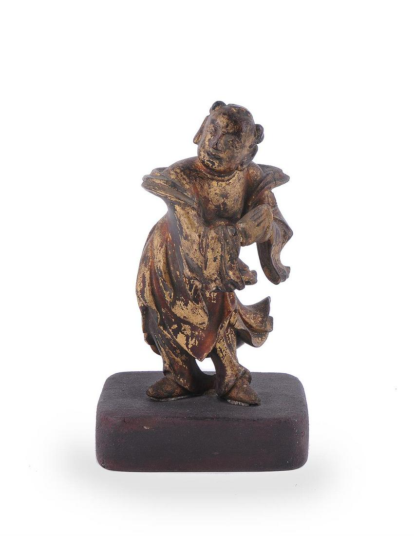 A Chinese gilt and lacquered wood figure of a boy: A Chinese gilt and lacquered wood figure of a boy, 17th century, fitted to a later wooden base, the figure 11.5cm highProvenance: From the collection of Sir David and Lady Scholey.明17世&#