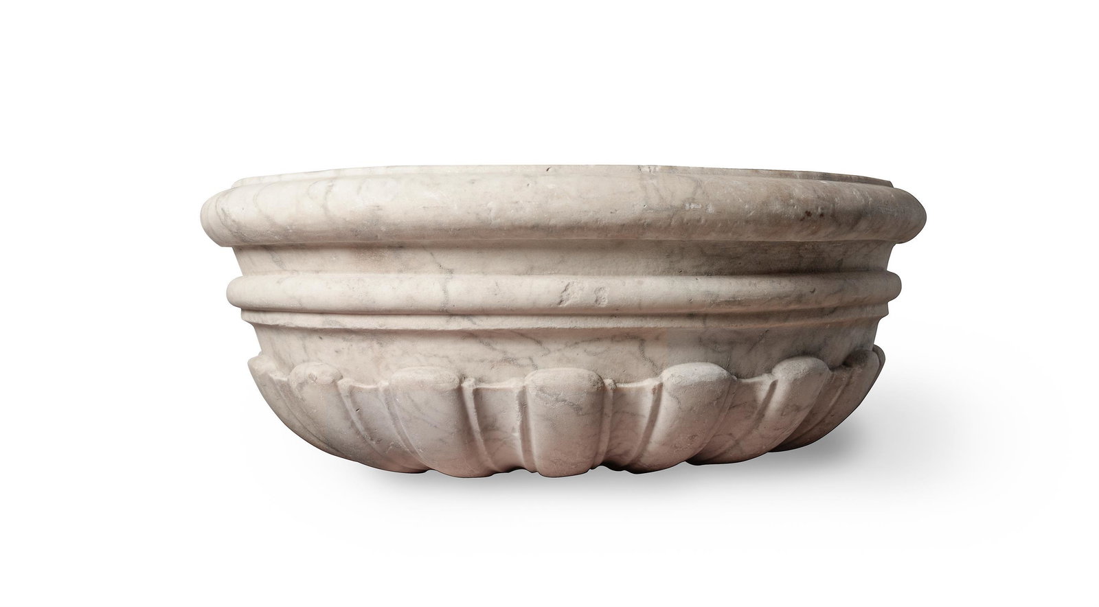 A 'GRAND TOUR' CARVED MARBLE CISTERN OR WINE COOLER, PROBABLY ITALIAN MID/LATE 18TH CENTURY: A 'GRAND TOUR' CARVED MARBLE CISTERN OR WINE COOLER PROBABLY ITALIAN MID/LATE 18TH CENTURY Of oval lobed form,61.5cm long, 52.5cm wide, 21cm high.This form of wine cooler is a reduced scale model afte