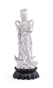 A well modelled Dehua figure of Guanyin: A well modelled Dehua figure of Guanyin, Qing Dynasty or Republic, holding a ruyi-sceptre and standing on a carp dragon with scrolling waves, with impressed seal mark 'Chen Wei', the figure 23cm high,