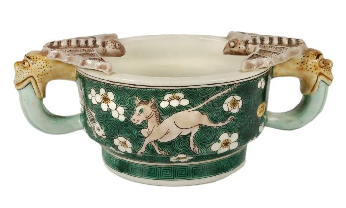 A Kangxi style famille verte censer of typical cir: A Kangxi style famille verte censer of typical circular form on a short foot, applied to either side with animal-head handles surmounted by bats, decorated in typical enamels on biscuit, the central w