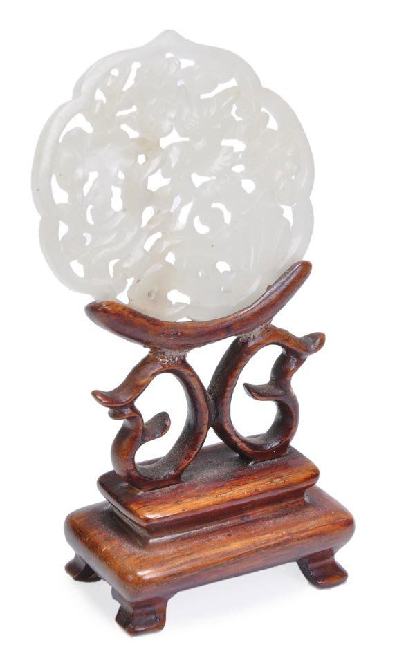 A small delicate white jade openwork plaque with e: A small delicate white jade openwork plaque with eight lobed border enclosing a bird on flowering prunus branches, 4.7cm wide, 18th-19th century, with fitted wood stand