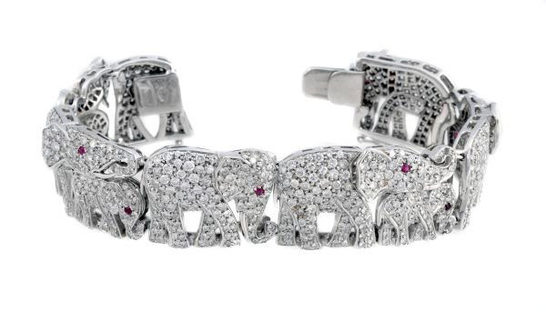 An Italian diamond and ruby bracelet, designed as: An Italian diamond and ruby bracelet, designed as an articulated line of six walking elephants with four elephant calves beneath their trunks, all pave set with brilliant cut diamonds, approximately 8