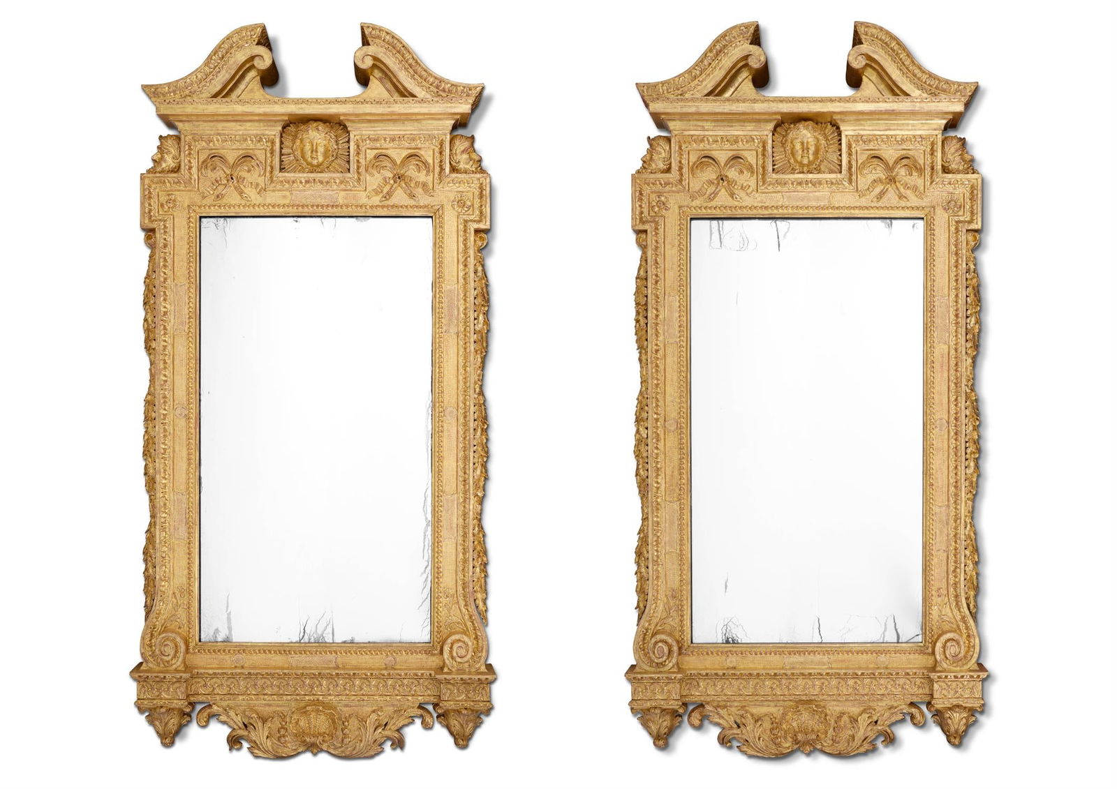‡ A PAIR OF GILTWOOD MIRRORS, CIRCA 1900: ‡ A PAIR OF GILTWOOD MIRRORSIN THE MANNER OF WILLIAM KENT, CIRCA 1900Each with a leaf-tip carved swan-neck pediment above a frieze centred by an Apollo mask and ribbon tied palms, the rectangular pl