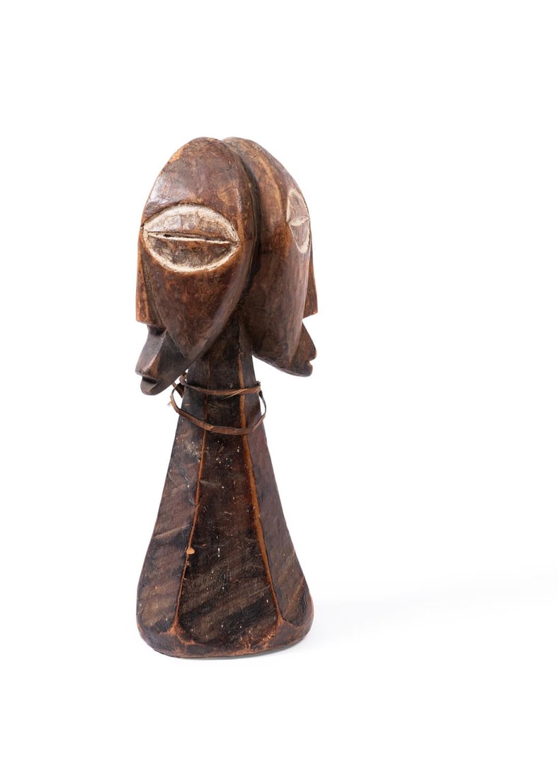 A BEMBE JANUS FIGURE: A BEMBE JANUS FIGURE DEMOCRATIC REPUBLIC OF CONGO, SECOND HALF 20TH CENTURY The conical neck supporting opposite faces with pointed chins and enlarged eyes, fibre plait around the neck, brown patina w
