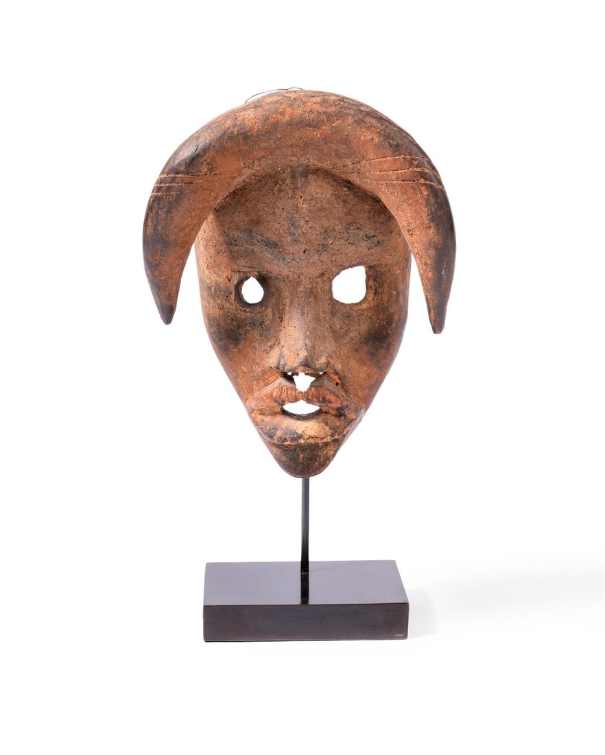 A DAN MASK , LIBERIA, CIRCA 1920: A DAN MASK REPUBLIC OF LIBERIA, CIRCA 1920 The elongated face with pointed chin, open mouth pierced rounded eyes, the domed forehead supporting two horns pointing downwards 27cm high
