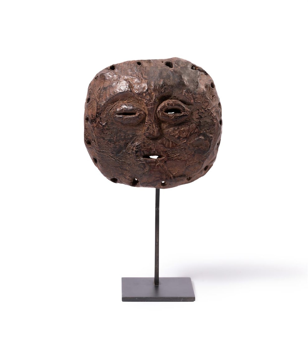 A WOODEN MASK, ZAMBIA, SECOND HALF 20TH CENTURY: A WOODEN MASK ZAMBIA, SECOND HALF 20TH CENTURY the rough face with pierced mouth and eyes, roughly carved holes around the edges for attachment, brown rich patina14cm high