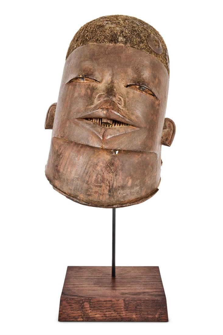 A MAKONDE HELMET MASK: A MAKONDE HELMET MASK CIRCA 1920 The face with exaggerated lips, spit eyes, all set under a coiffure with inlaid hair 27cm high Provenance: Tribal Gathering, London
