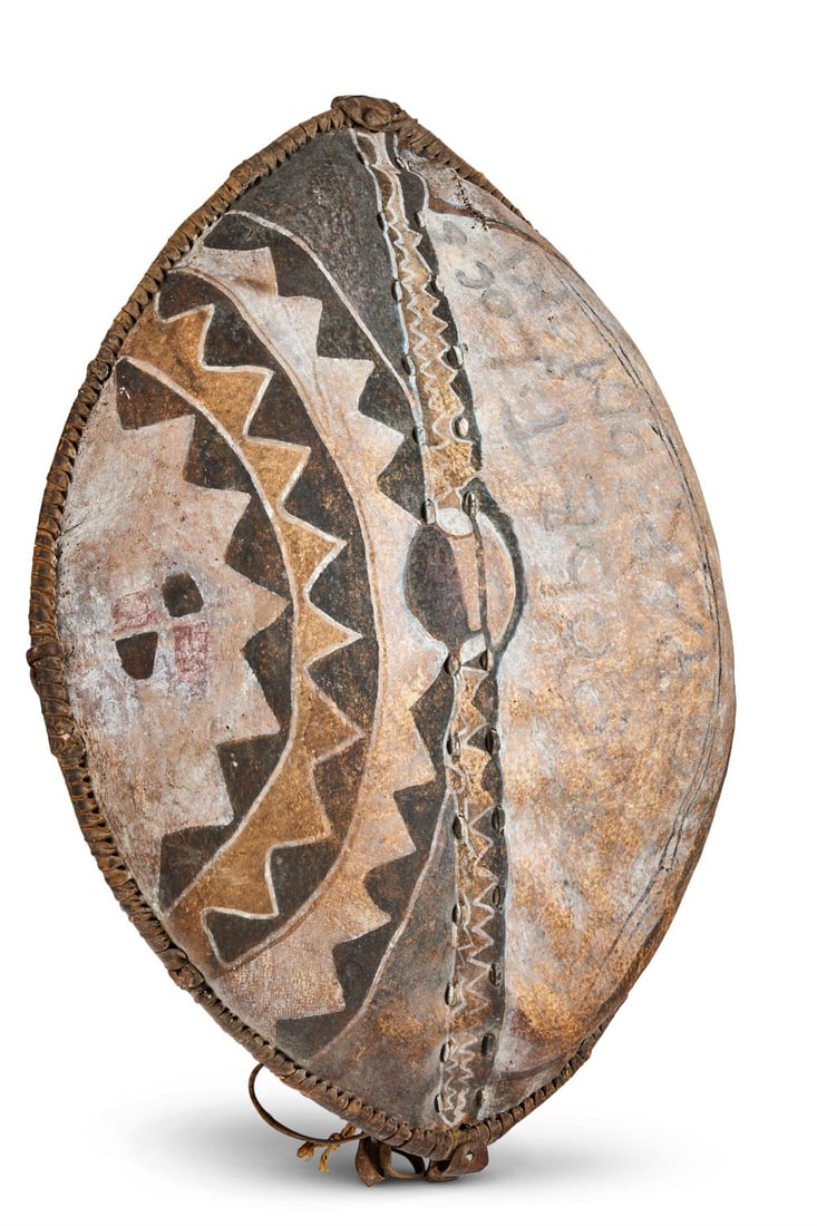 A KIKUYU HIDE SHIELD: A KIKUYU HIDE SHIELD KENYA, FIRST HALF 20TH CENTURY Of almond shape, decorated with painted geometric motifs in ochre colours 99cm high Provenance: Tribal Gathering, London