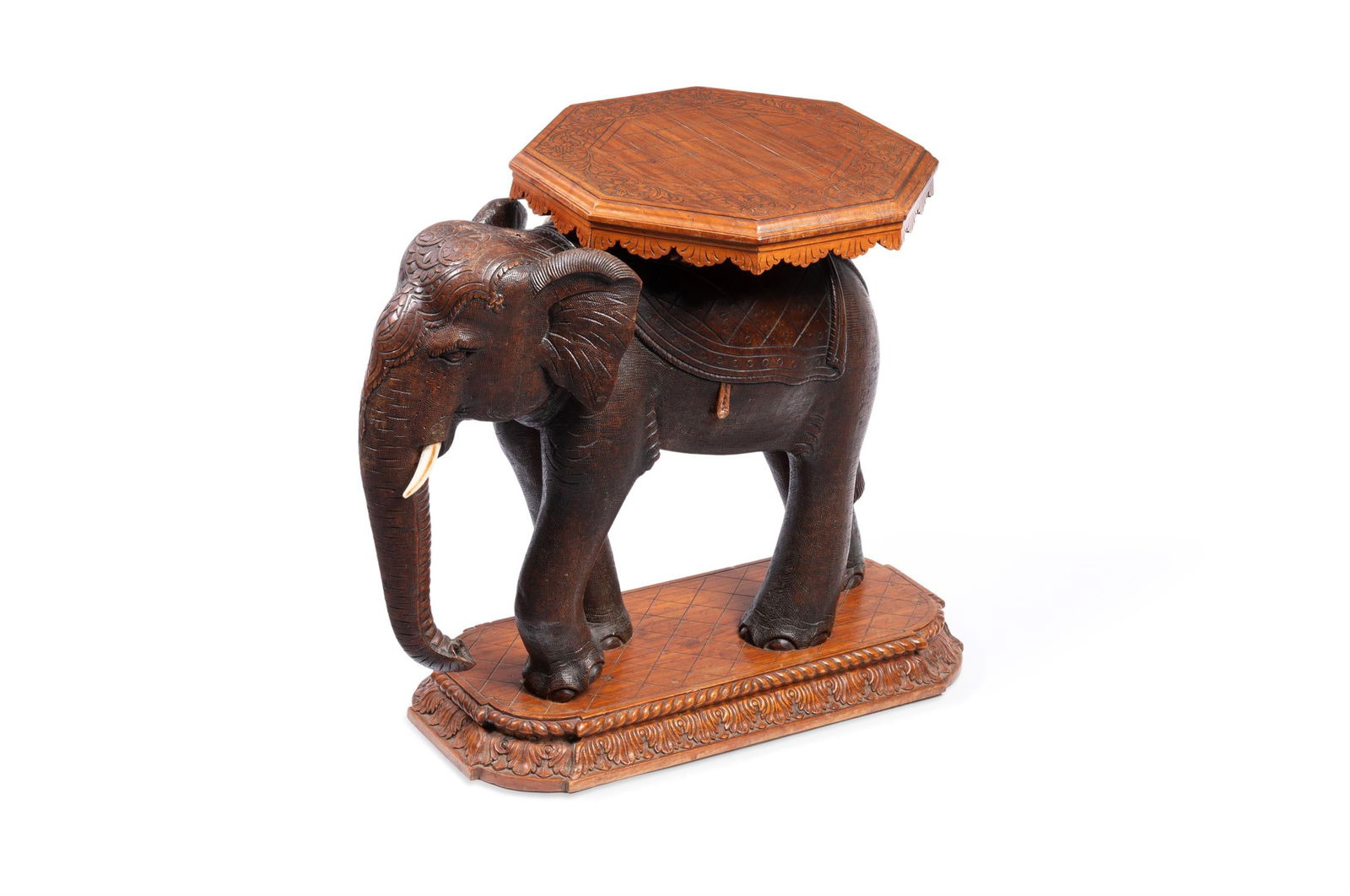 AN ELEPHANT STOOL: AN INDIAN CARVED HARDWOOD AND IVORY OCCASIONAL TABLE MODELLED AS AN ELEPHANT19TH CENTURY, POSSIBLY BARODAThe elephant supporting an octagonal platform with incised decoration and lapetted edge, on a r