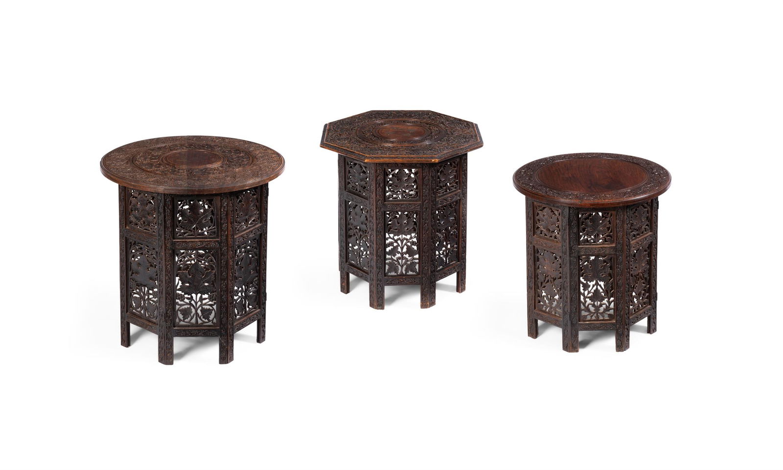 AN INDIAN BRASS-INLAID HARDWOOD OCCASIONAL TABLE, EARLY 20TH CENTURY: AN INDIAN BRASS-INLAID HARDWOOD OCCASIONAL TABLEEARLY 20TH CENTURYThe circular top carved with fruiting vines and strapwork arches on a conforming pierced base carved with leaves56cm high, 54cm