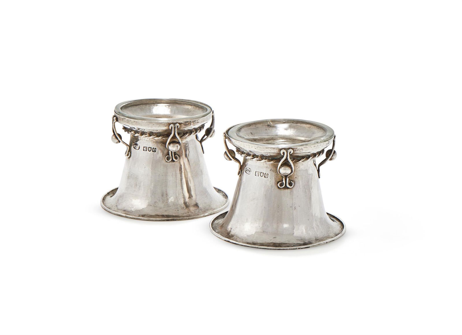 A PAIR OF VICTORIAN SILVER TRENCHER SALTS: A PAIR OF VICTORIAN SILVER TRENCHER SALTSOMAR RAMSDEN & ALWYN CARR, LONDON 1900With cable twist bands, bead and scroll supports10cm diameter234g (7.5 oz)With two glass liners Provenance:An Anglo-Frenc