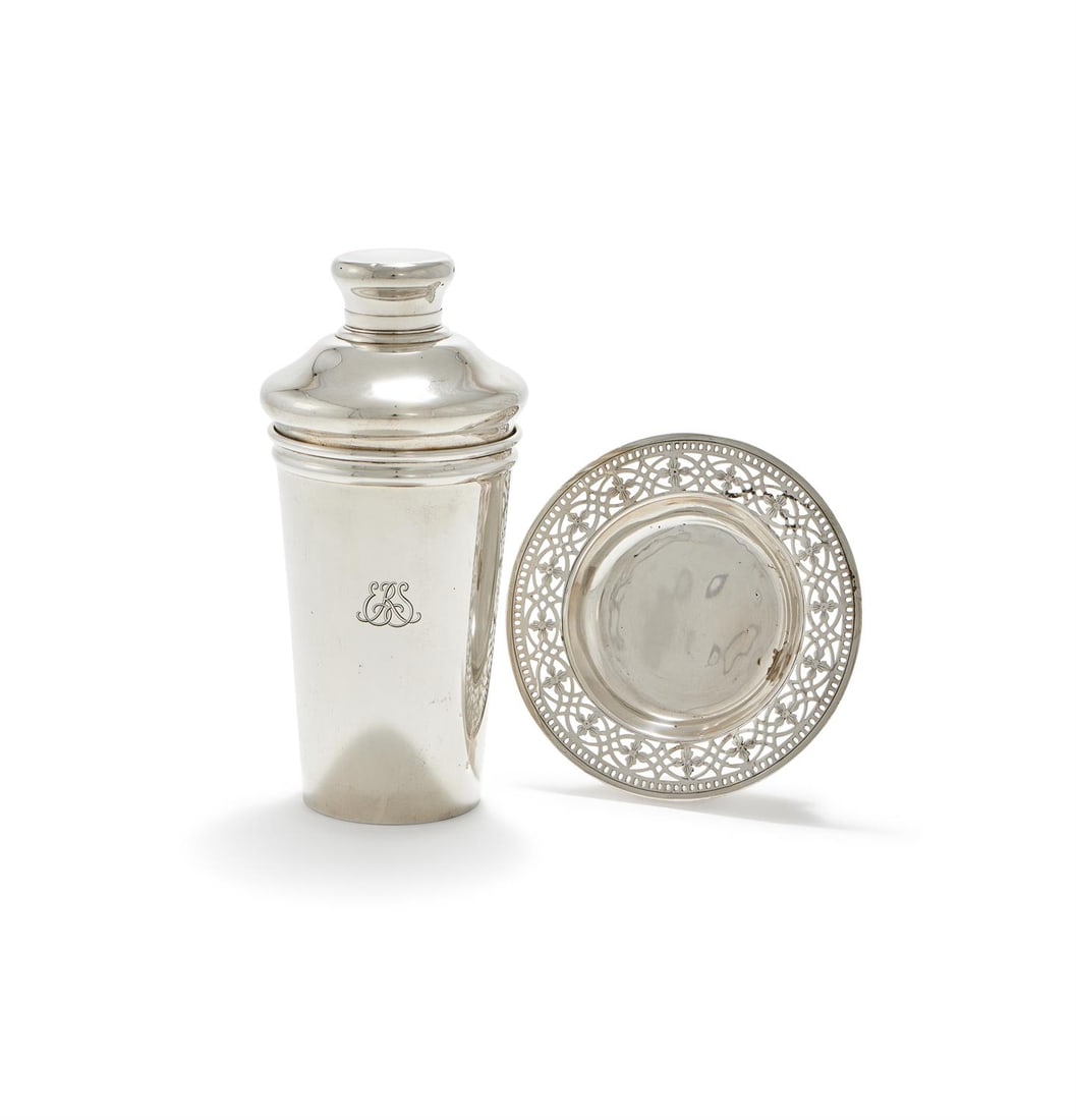 AN AMERICAN SILVER COCKTAIL SHAKER AND A DISH: AN AMERICAN SILVER COCKTAIL SHAKER AND A DISHTIFFANY & CO., CIRCA 1920The cocktail shaker with a domed cover and tapering body, engraved ERS, the dish with a pierced scroll border and on a circular
