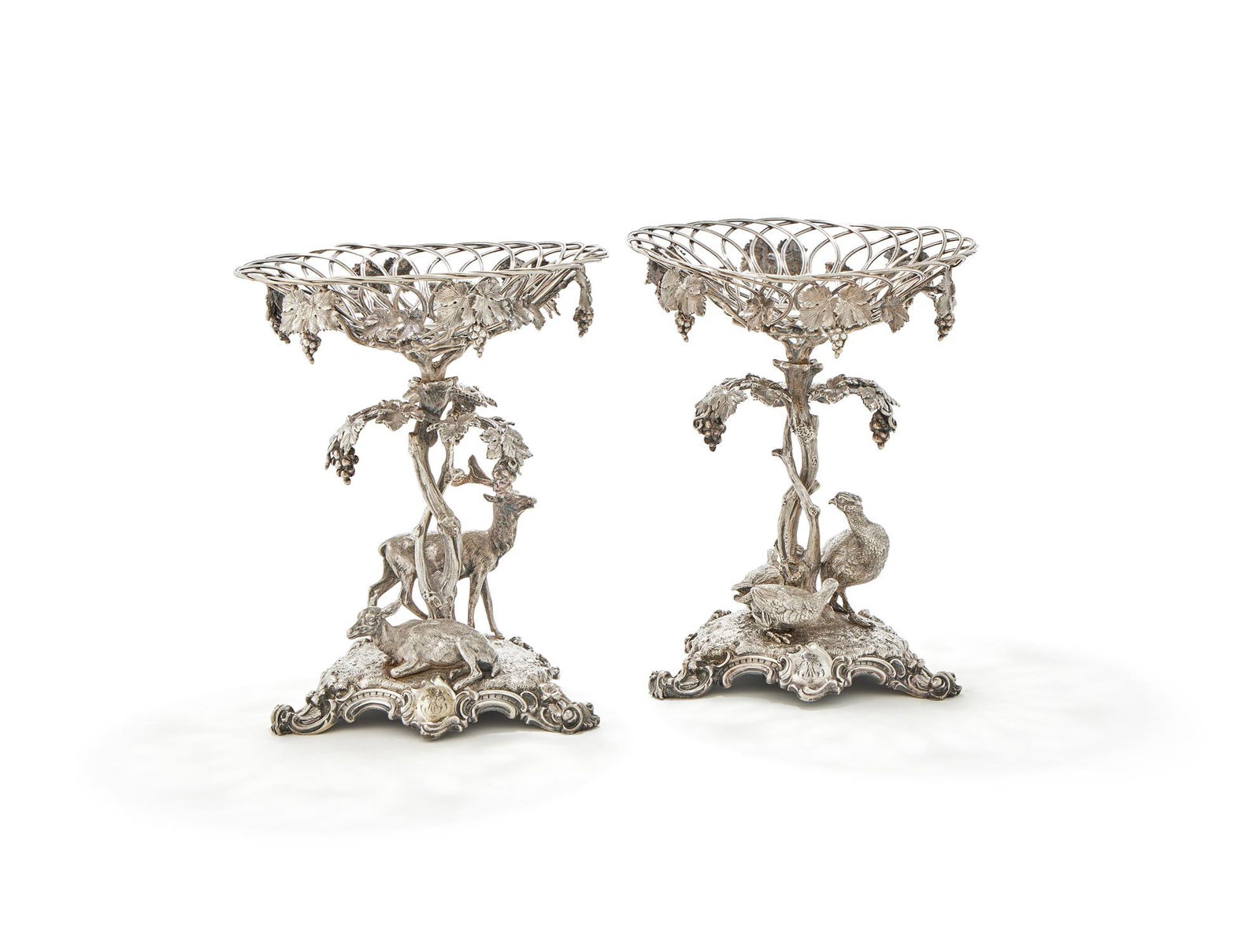 A PAIR OF VICTORIAN ELECTRO-PLATED CENTREPIECES: A PAIR OF VICTORIAN ELECTRO-PLATED CENTREPIECESUNMARKEDWith wirework baskets suspending grapes, one with a stag and a doe beneath, the other with three pheasants, with grape vine stems to trefoil shap