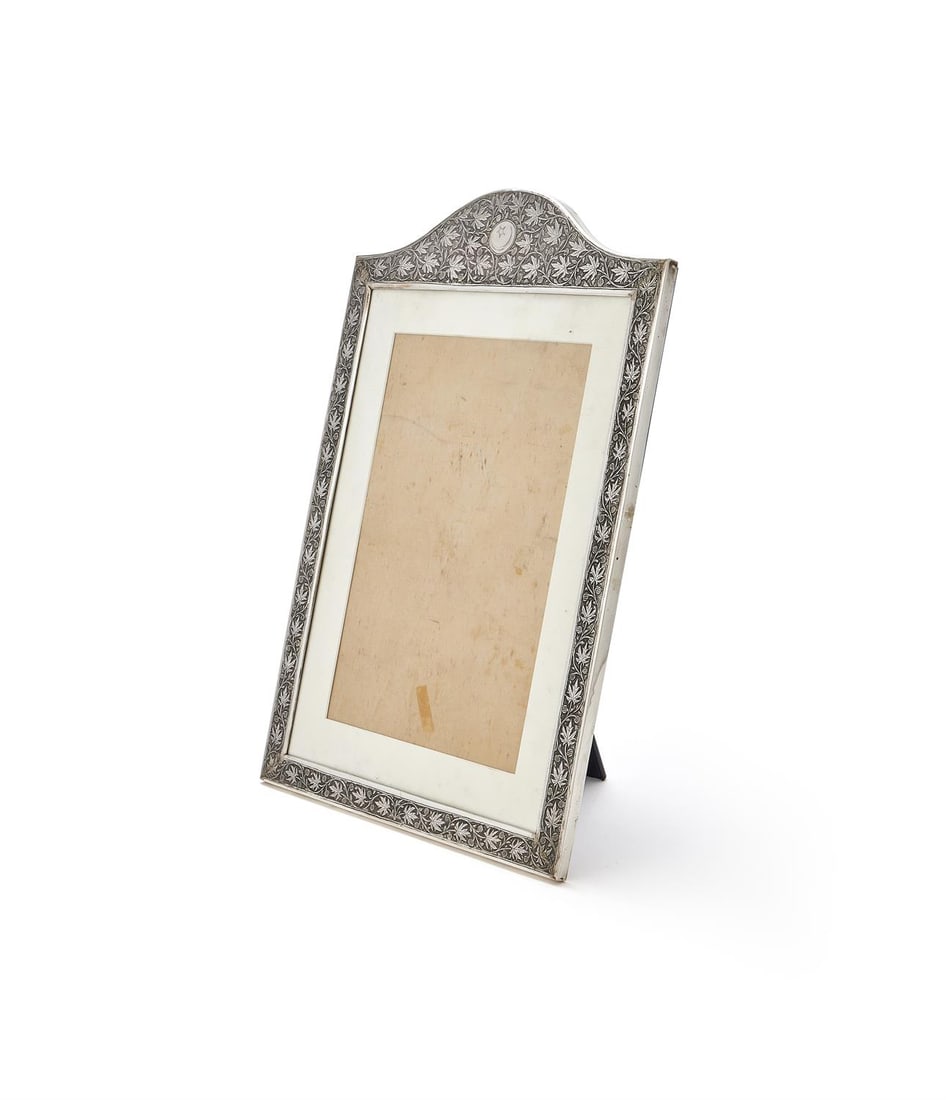 A LARGE SILVER MOUNTED PHOTO FRAME: A LARGE SILVER MOUNTED PHOTO FRAMEUNMARKEDWith a chased and engraved foliate border and a crescent moon and star within a circular reserve 52cm high