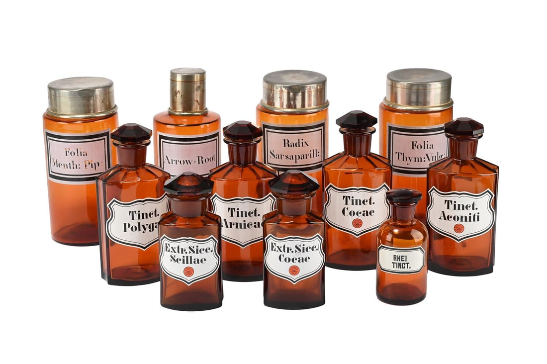 A SELECTION OF AMBER GLASS DRUG JARS AND COVERS, IN 19TH CENTURY STYLE: A SELECTION OF AMBER GLASS DRUG JARS AND COVERS IN 19TH CENTURY STYLE Each with titled cartouche, some with glass stoppers, others with metal the tallest 23.5cm high, the smallest