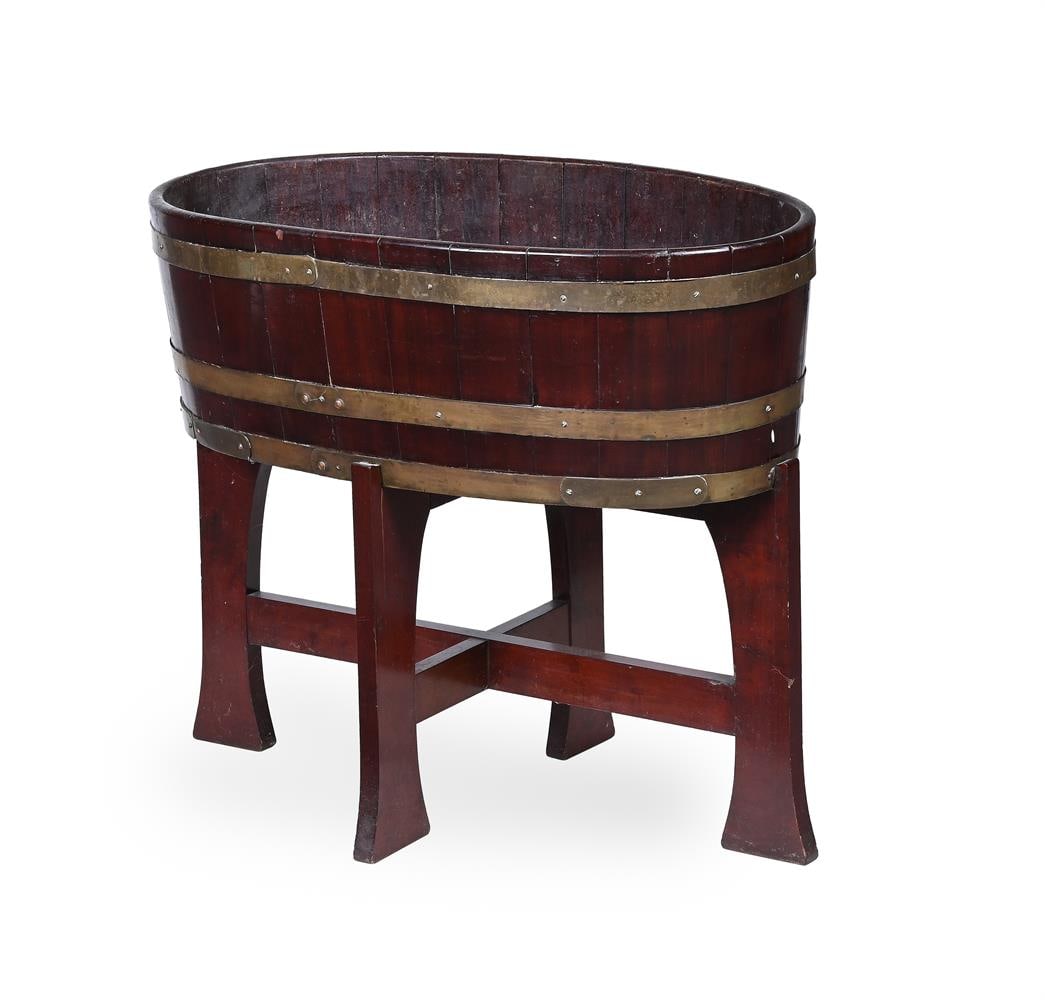 A GEORGE III MAHOGANY WINE COOLER OR JARDINIERE ON STAND, CIRCA 1800: A GEORGE III MAHOGANY WINE COOLER OR JARDINIERE ON STAND CIRCA 1800 The oval coopered body, zinc drip liner, and brass banding 68cm high, 79cm wide, 43cm deep, inside depth of the