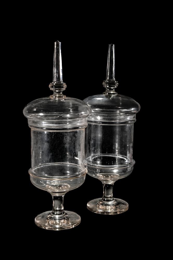 A PAIR OF CLEAR GLASS PEDESTAL CHEMIST JARS AND COVERS: A PAIR OF CLEAR GLASS PEDESTAL CHEMIST JARS AND COVERS
