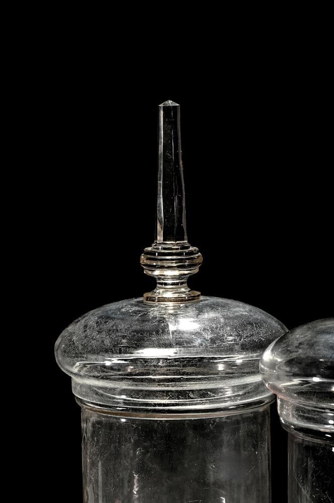 A PAIR OF CLEAR GLASS PEDESTAL CHEMIST JARS AND COVERS - 2