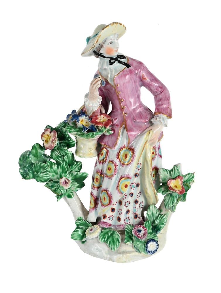 A BOW PORCELAIN MODEL OF A 'FLOWER GIRL', CIRCA 1760: A BOW PORCELAIN MODEL OF A 'FLOWER GIRL' CIRCA 1760 Modelled standing with a basket of flowers before bocage, traces of dagger mark 16cm high, 13cm wide Note The