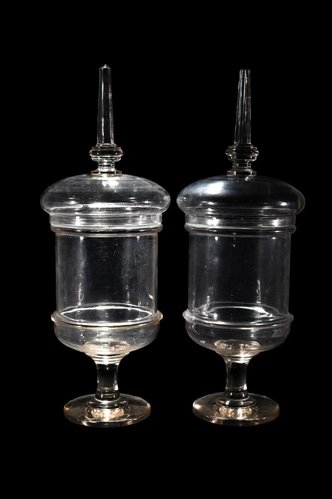 A PAIR OF CLEAR GLASS PEDESTAL CHEMIST JARS AND COVERS: A PAIR OF CLEAR GLASS PEDESTAL CHEMIST JARS AND COVERS