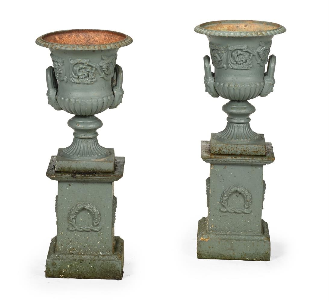 A SMALL PAIR OF CAST IRON URNS ON STANDS IN THE HANDYSIDE PATTERN, 20TH CENTURY (1 of 3)