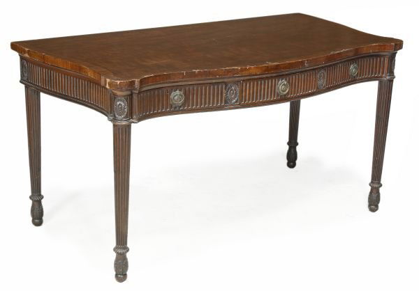 A mahogany serving table, in George III style , ci: A mahogany serving table, in George III style, circa 1900, serpentine front and sides, crossbanded top, fluted frieze flanked by stylised flowerheads within oval beaded surround, one large and one sma